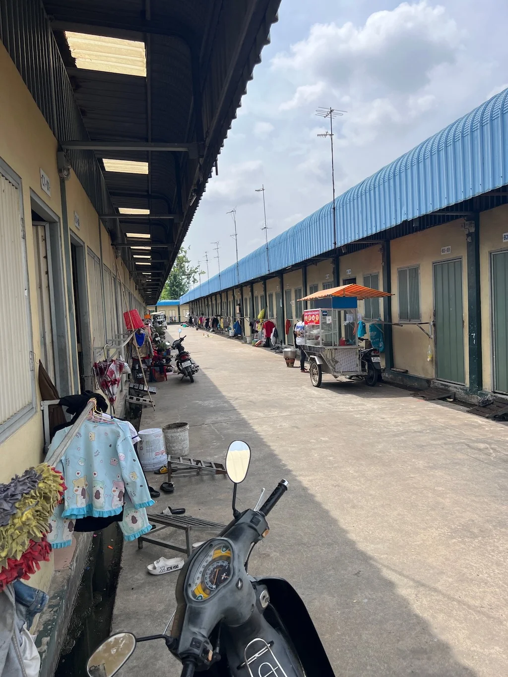 A walkway between factory buildings with bicycles parked outside.