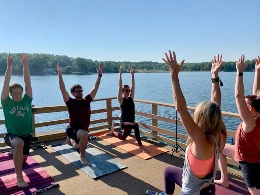 CPL Investments team members stretch together on a lakeside deck.