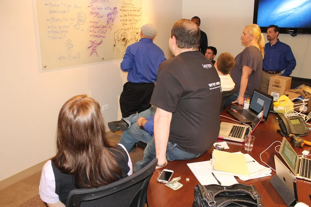 Lextech team members discuss culture ideas around a whiteboard.